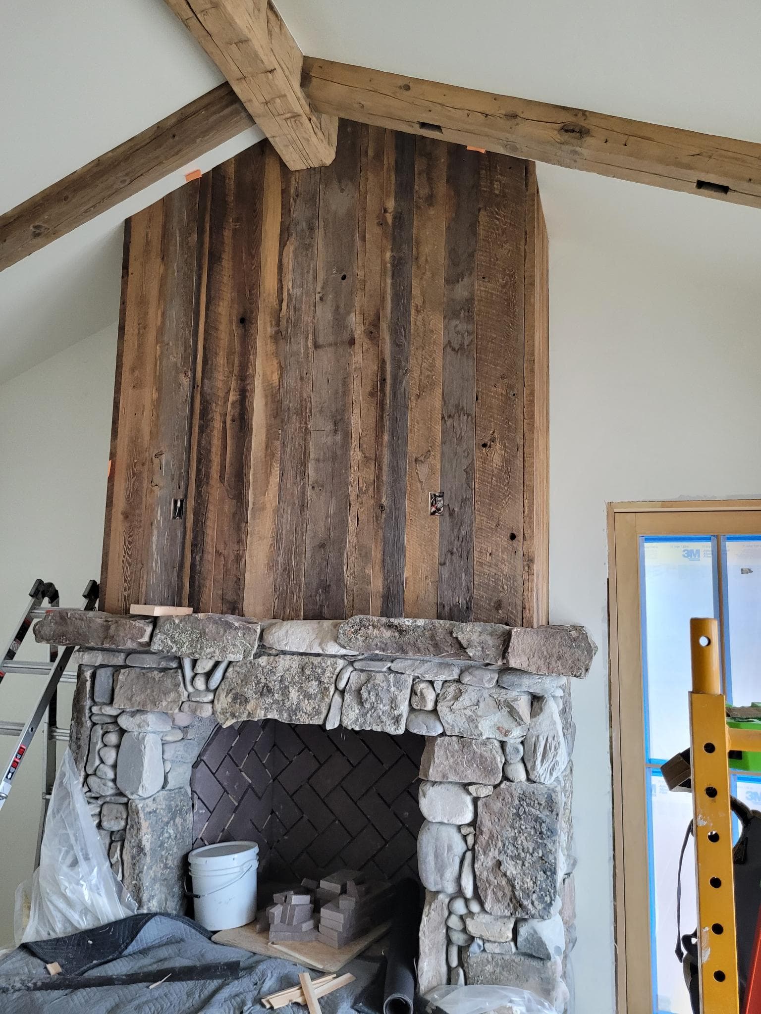 Rustic stone fireplace with reclaimed wood paneling and exposed ceiling beams