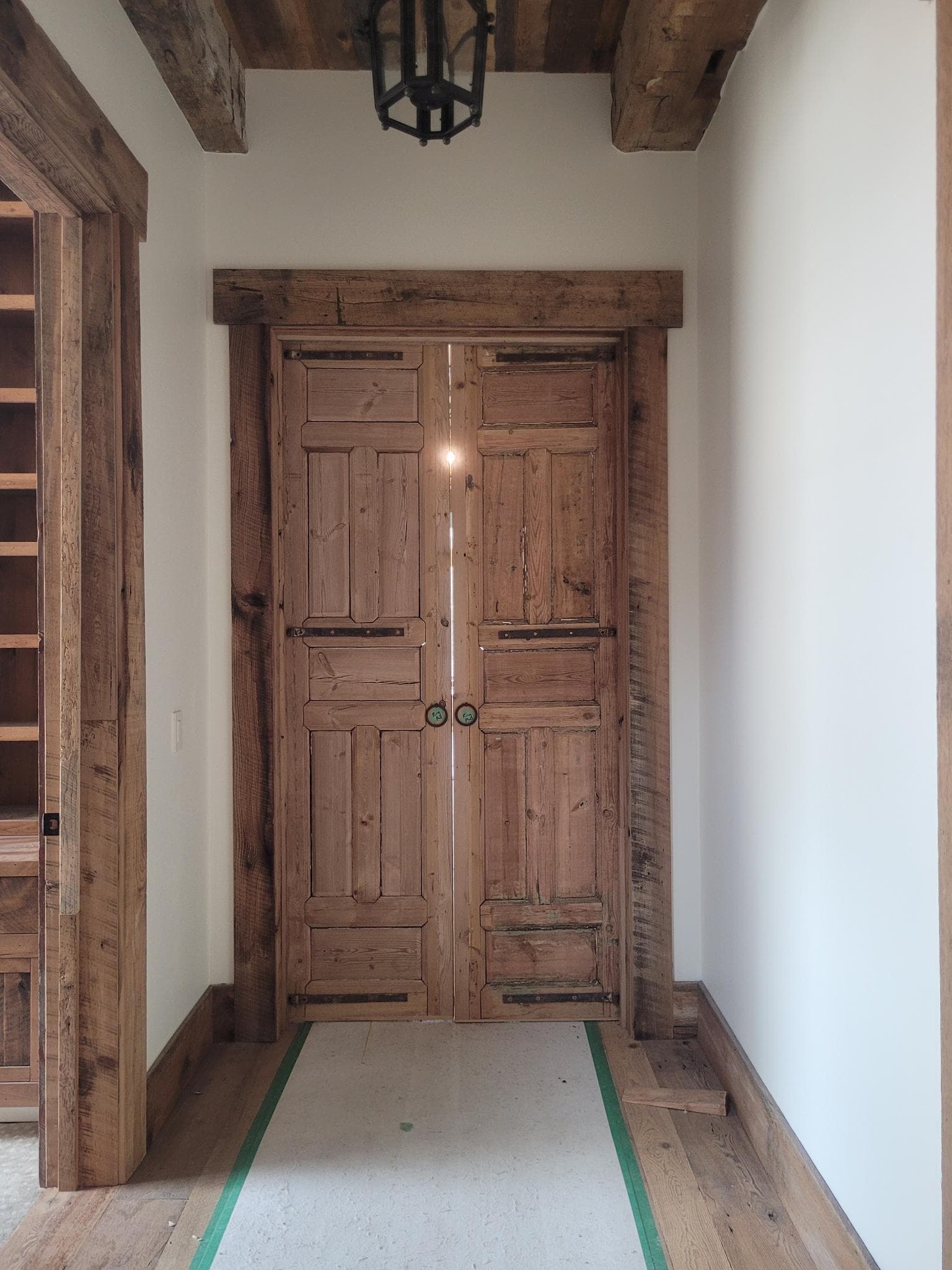 Rustic double wood doors with reclaimed timber frame in a hallway