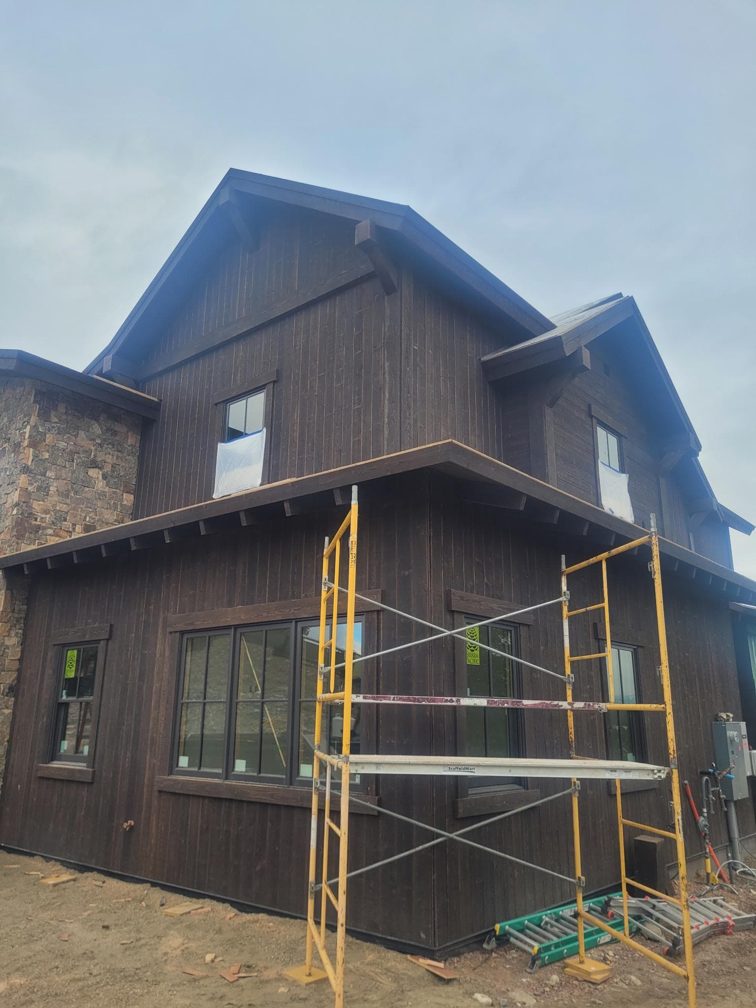 Exterior corner of custom home with scaffolding and stone cladding