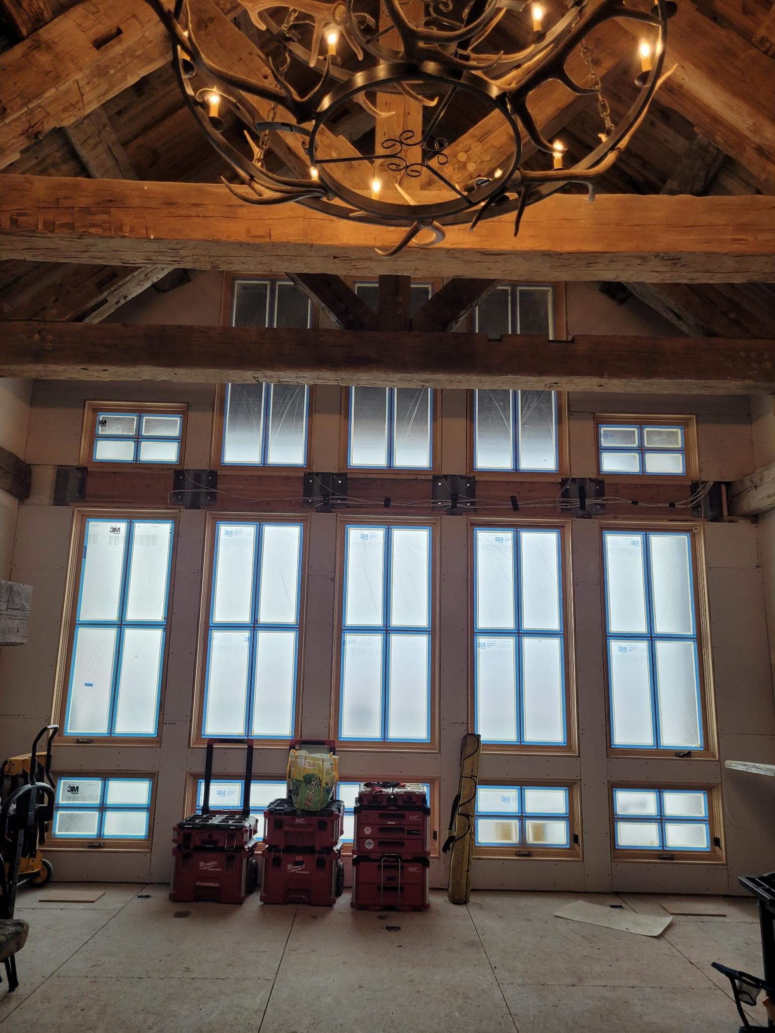 Great room window wall with timber beams and antler chandelier