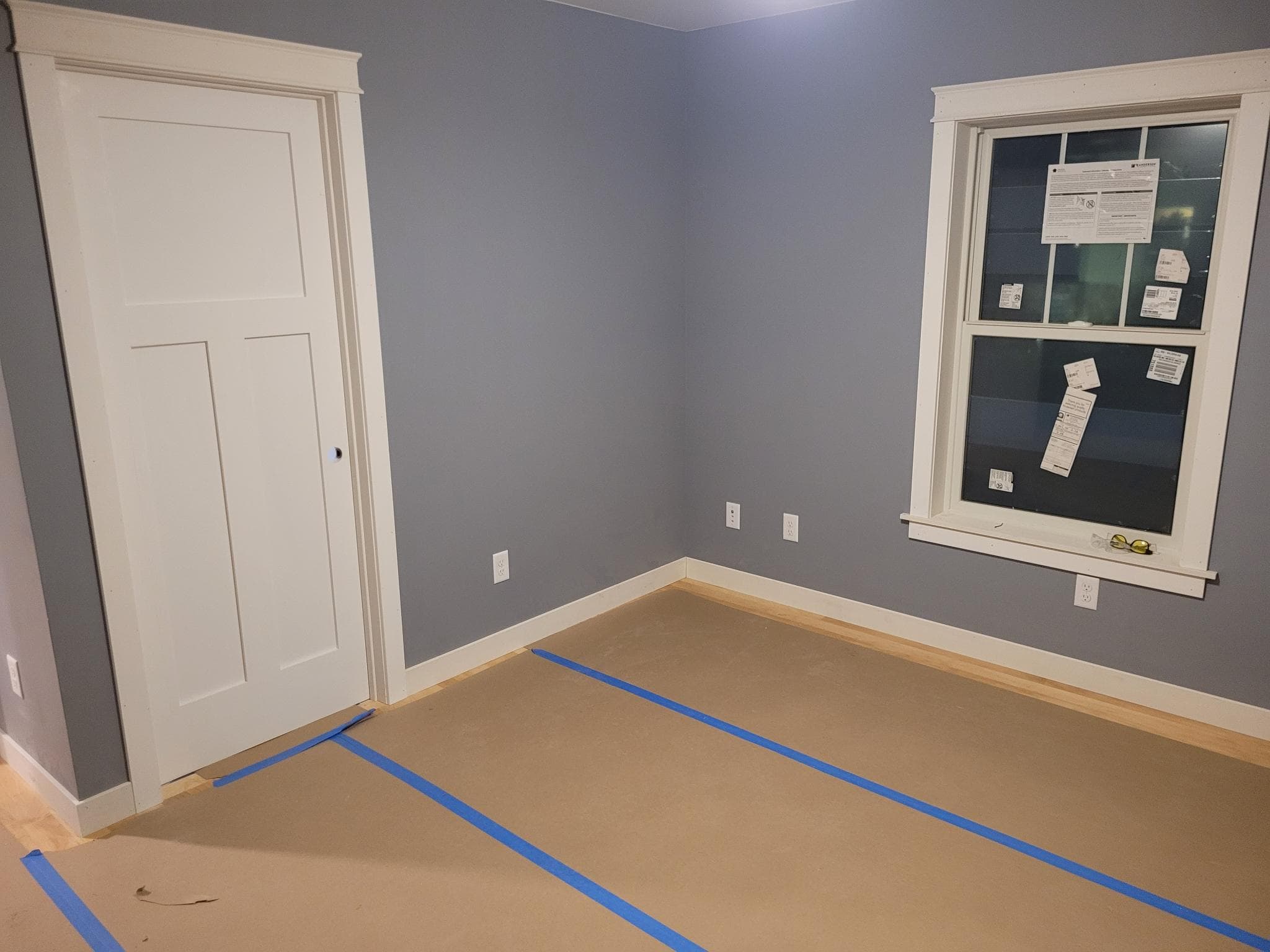 Bedroom interior with blue-gray walls, white craftsman trim, and protected hardwood floors