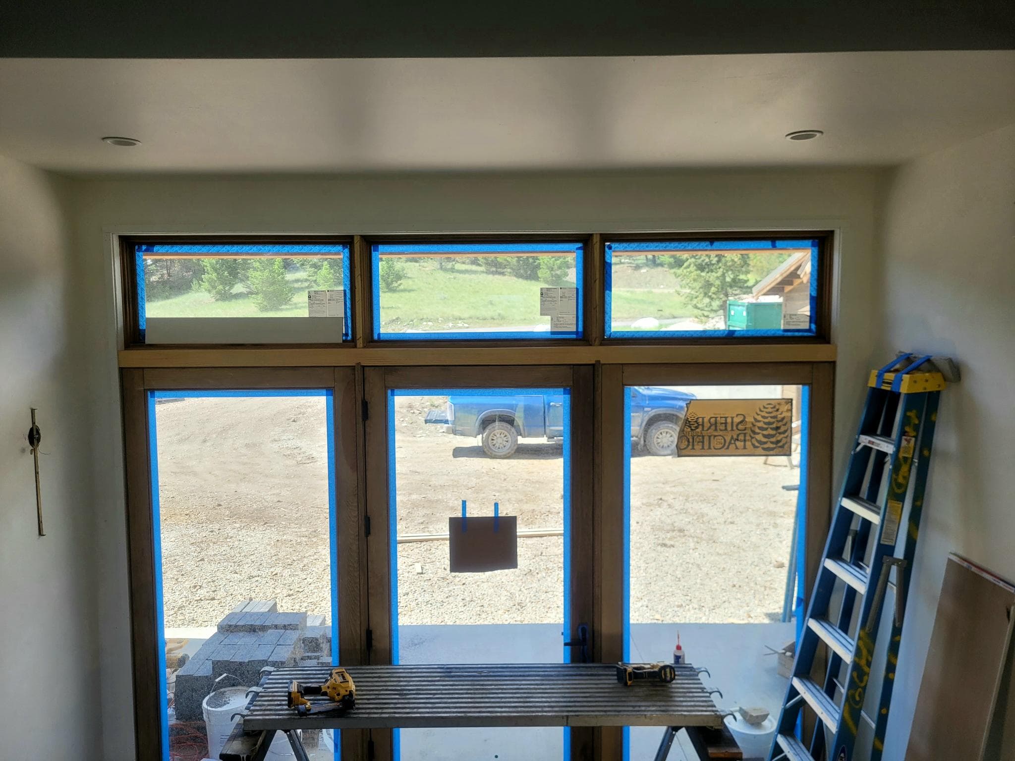 Large wood-framed door and transom window assembly during installation