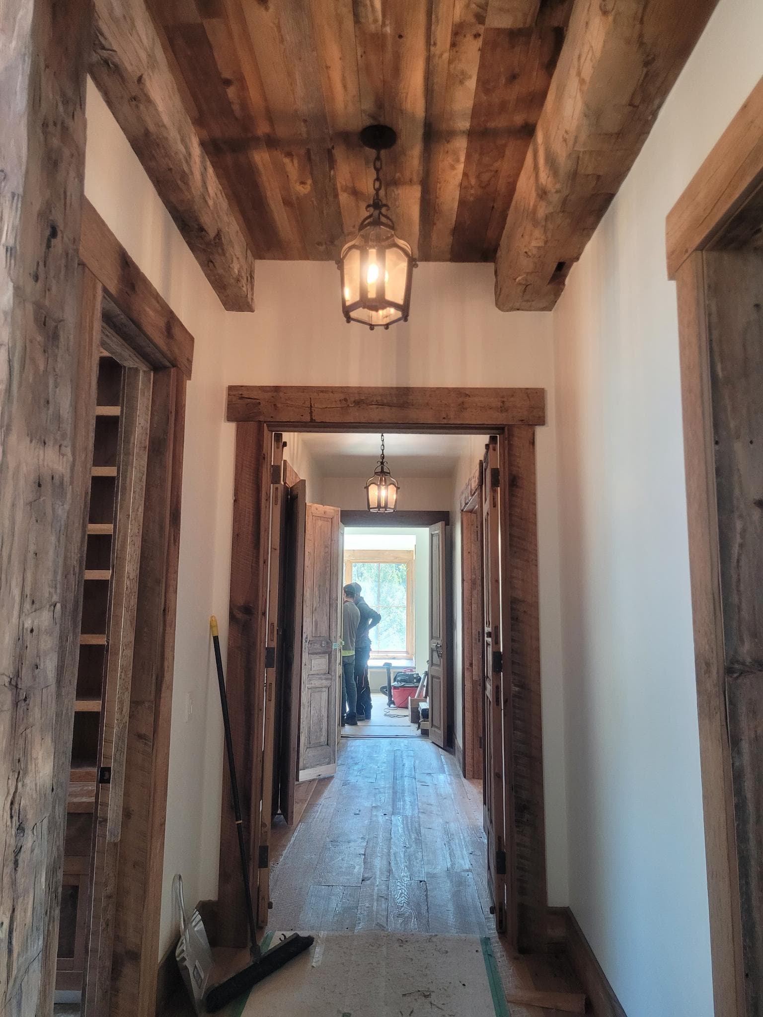 Hallway with reclaimed wood ceiling, beams, and custom wood doors