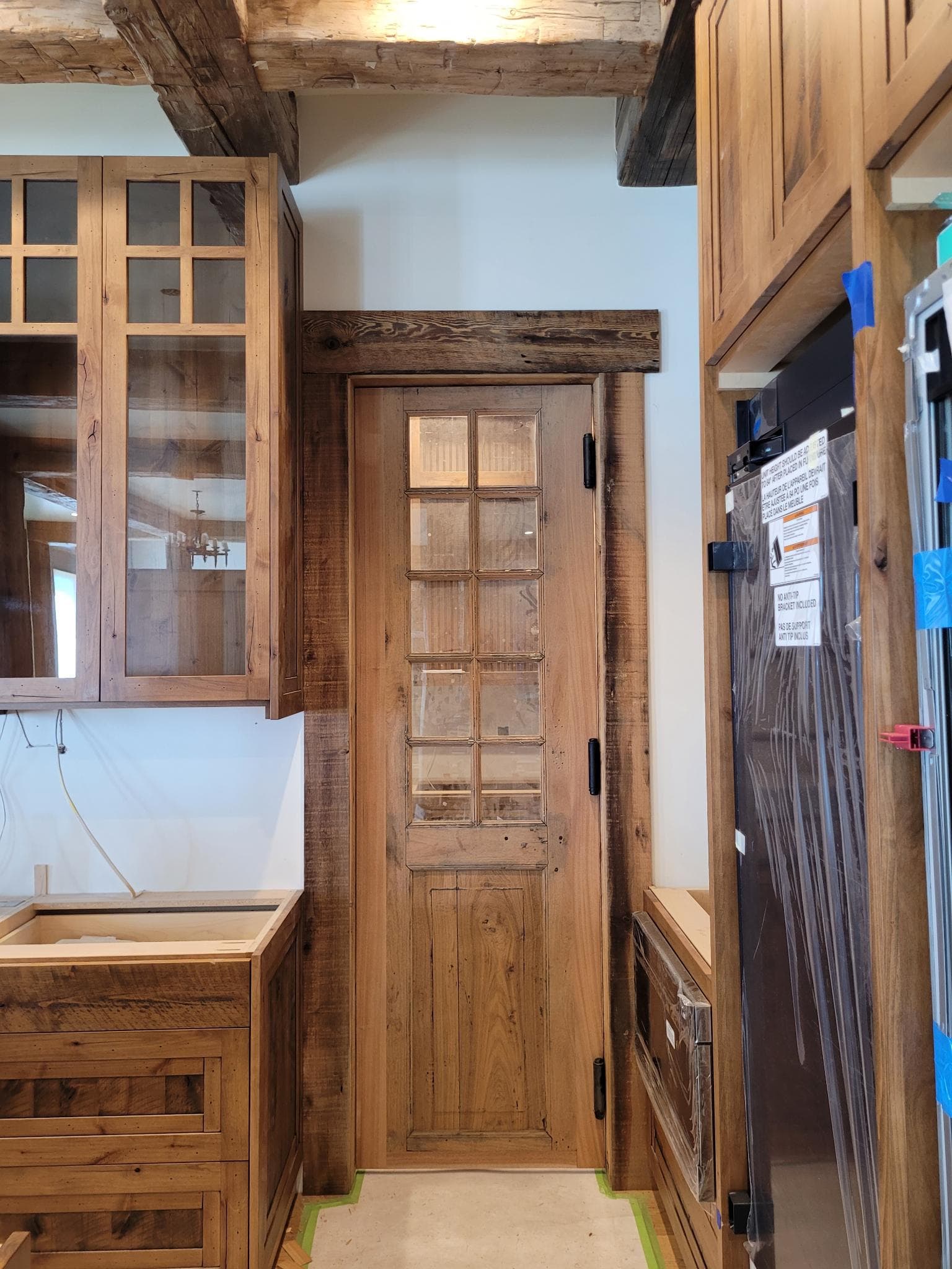 Rustic kitchen with custom wood cabinetry and glass-paneled pantry door